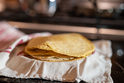 A stack of warm, handmade tortillas next to a plate of golden milanesa tacos.