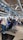 A busy airport check-in area with passengers lining up at the counters. People are handling their luggage, and there are various signs displaying flight information. The environment is crowded, with many travelers preparing for their flights.