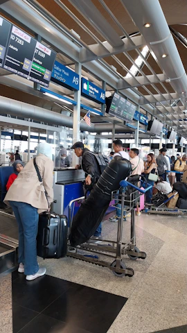 A friendly travel consultant assisting a happy traveler with luggage at an airport counter.