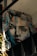 A large, expressive mural portrays a woman's face in a realistic yet artistic style. The painting features dynamic brush strokes with a mix of bright and dark colors, giving it a dramatic appearance. The artwork is situated on an interior wall with visible beams and other architectural elements around it.