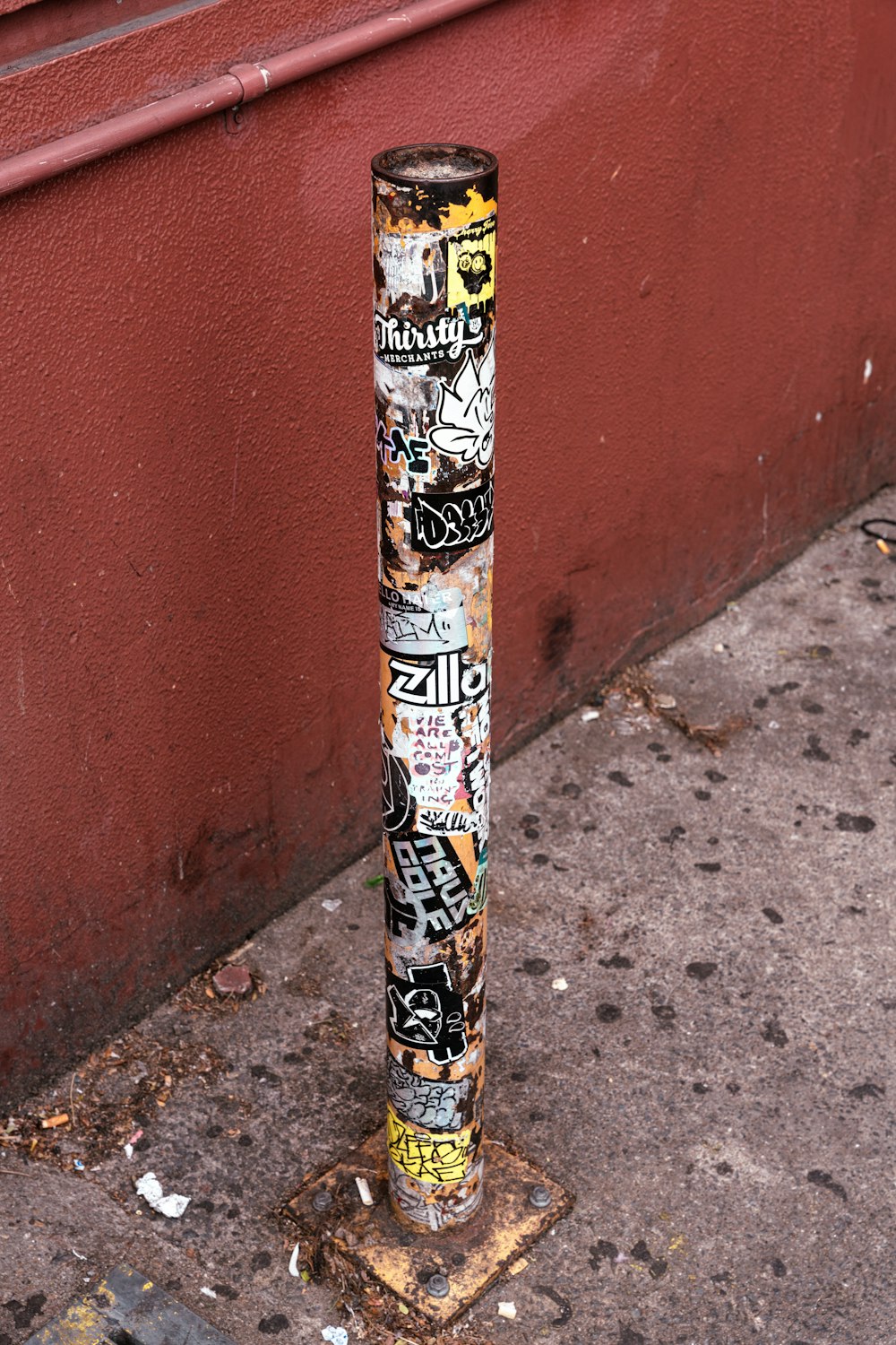 a pole covered in graffiti on the side of a street