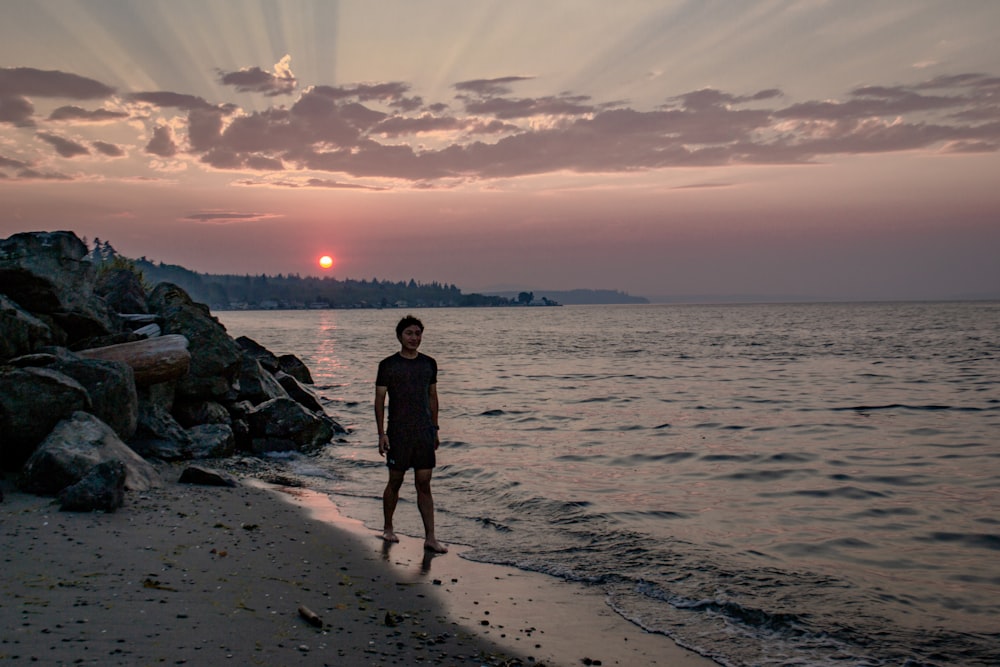 a man standing on a beach next to the ocean