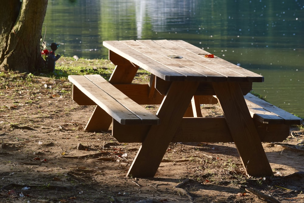 a wooden picnic table sitting next to a lake