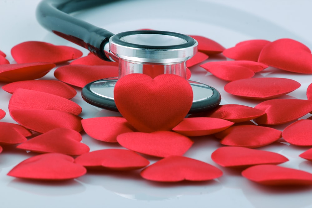 a stethoscope on top of a pile of red hearts