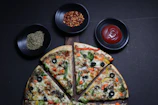 A colorful veggie pizza topped with fresh bell peppers, olives, and tomatoes on a wooden table.