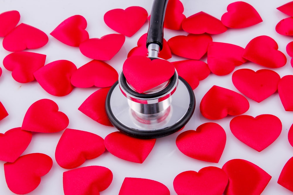 a stethoscope surrounded by hearts on a white surface