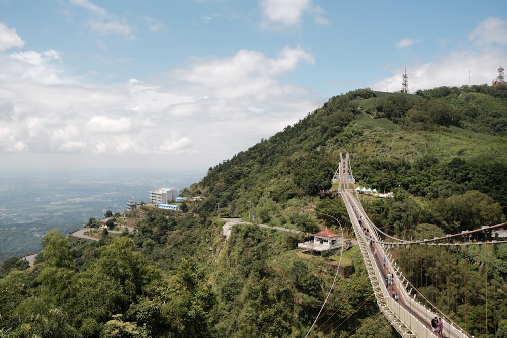 a long suspension bridge over a lush green hillside