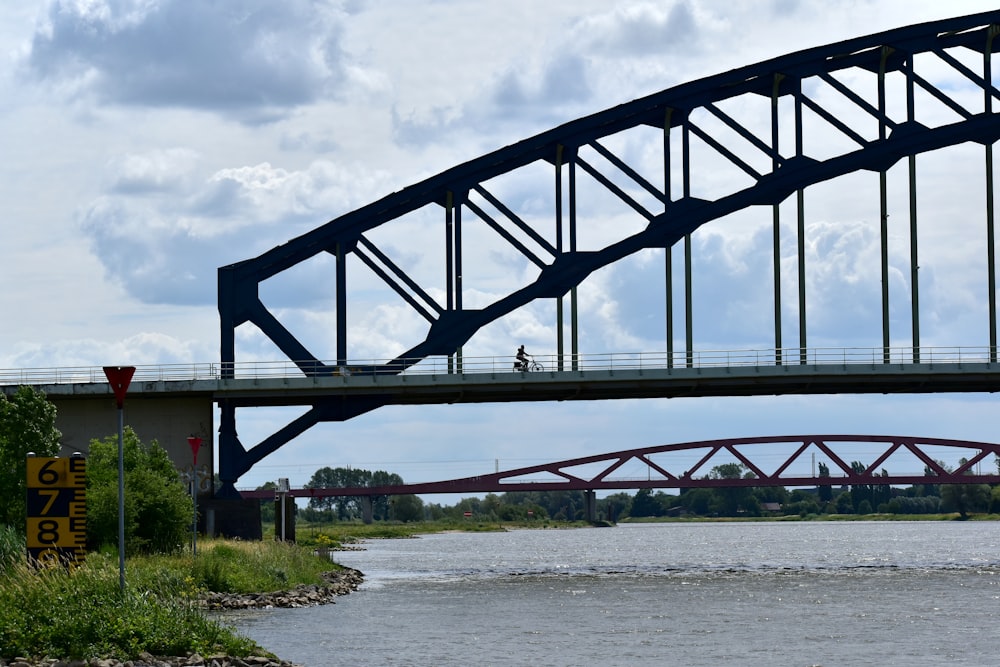 a man riding a bike across a bridge over a river