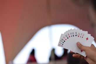 Hands holding winning 3patti gold cards with a blurred game table background.