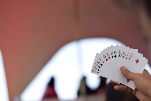 Hands holding winning 3patti gold cards with a blurred game table background.