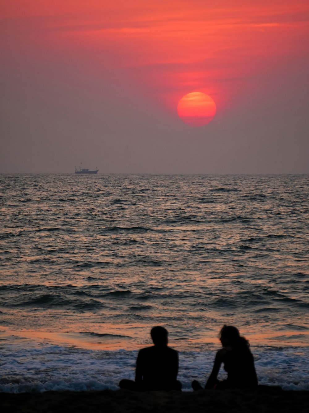 a couple of people sitting on top of a beach