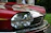Close-up of a gleaming restored classic Jaguar's polished chrome grille under soft lighting.