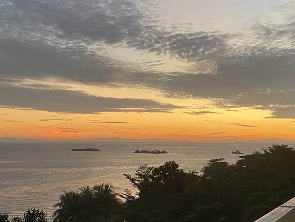 A sunset over the ocean with silhouettes of ships.