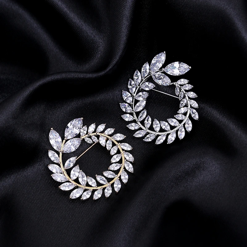 Pair of diamond leaf climber earrings forming open wreaths on black satin