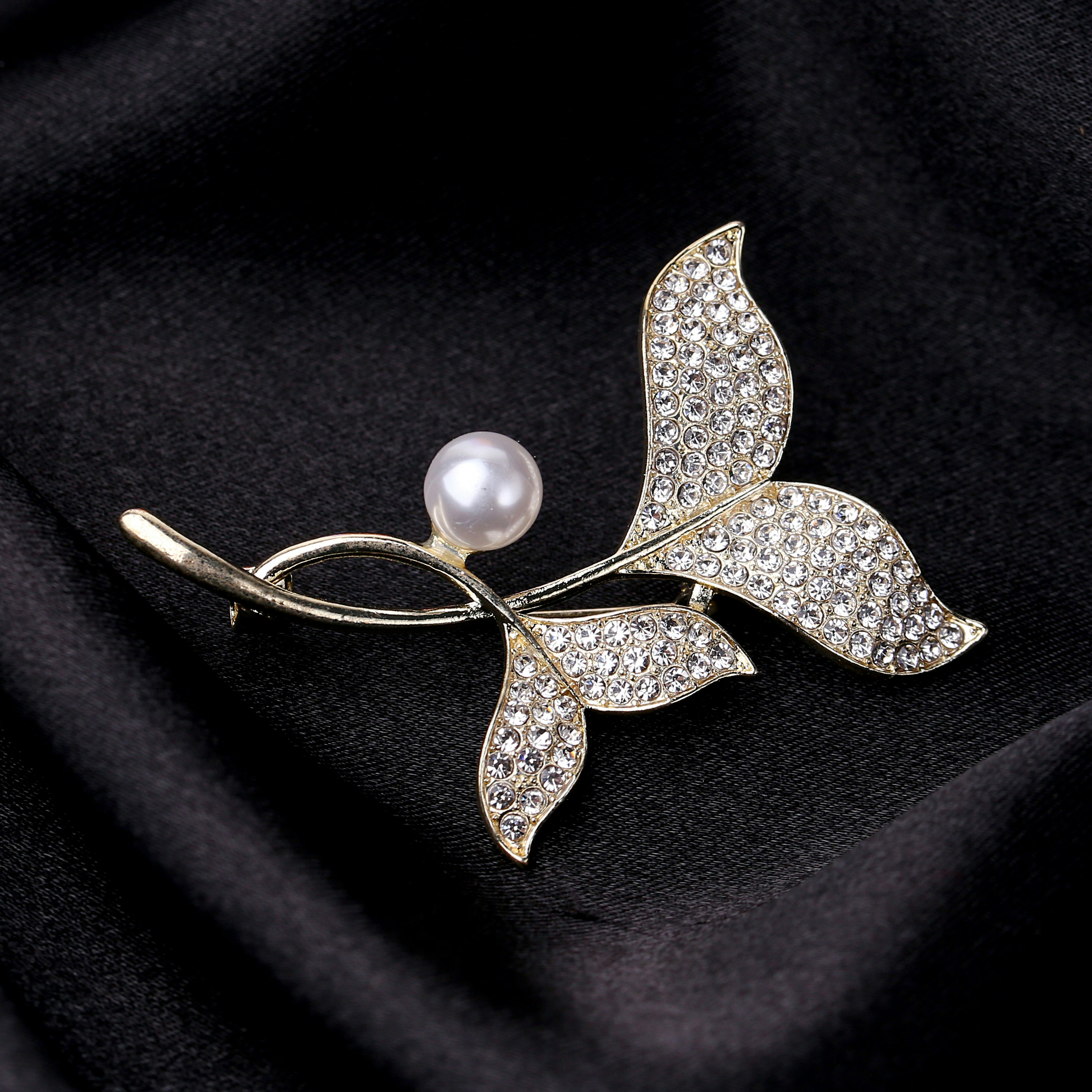 a brooch with a leaf and a pearl