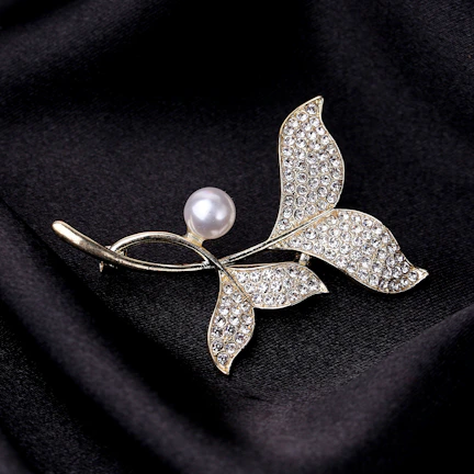 Close-up of a coffee petal brooch showing delicate pearl and metallic textures.
