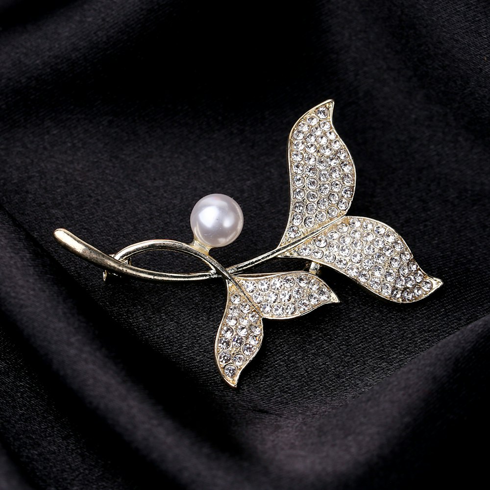 a brooch with a leaf and a pearl