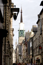 a narrow city street with a church steeple in the background