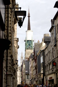 a narrow city street with a church steeple in the background