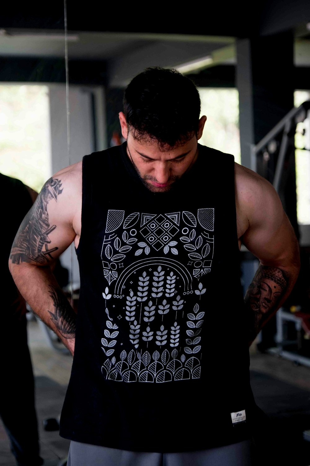 a man with a tattoo on his arm standing in a gym