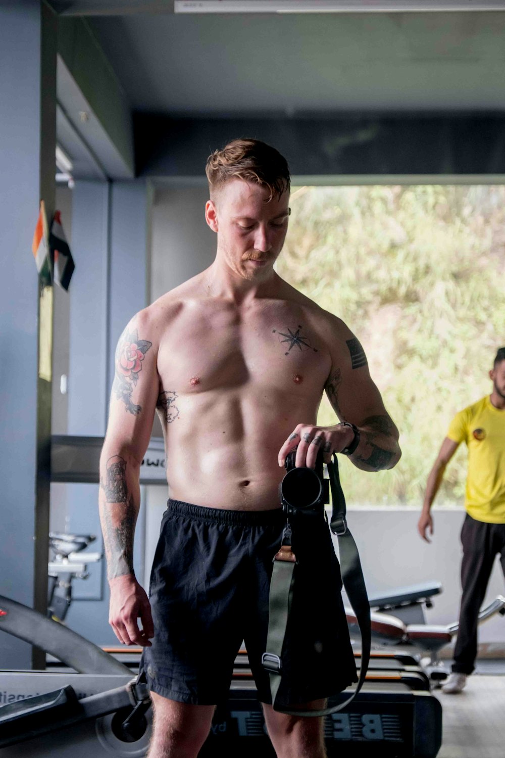 a shirtless man holding a gym bag in a gym