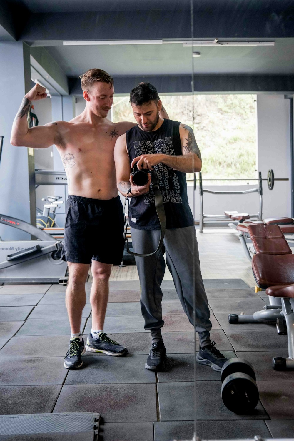 a couple of men standing next to each other in a gym