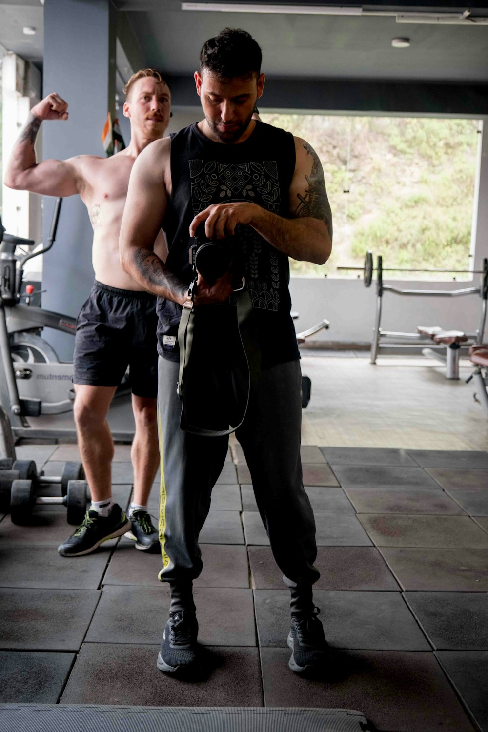 a man with no shirt on standing next to another man in a gym