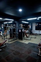 Dimly lit gym interior with sleek black equipment and ambient lighting.