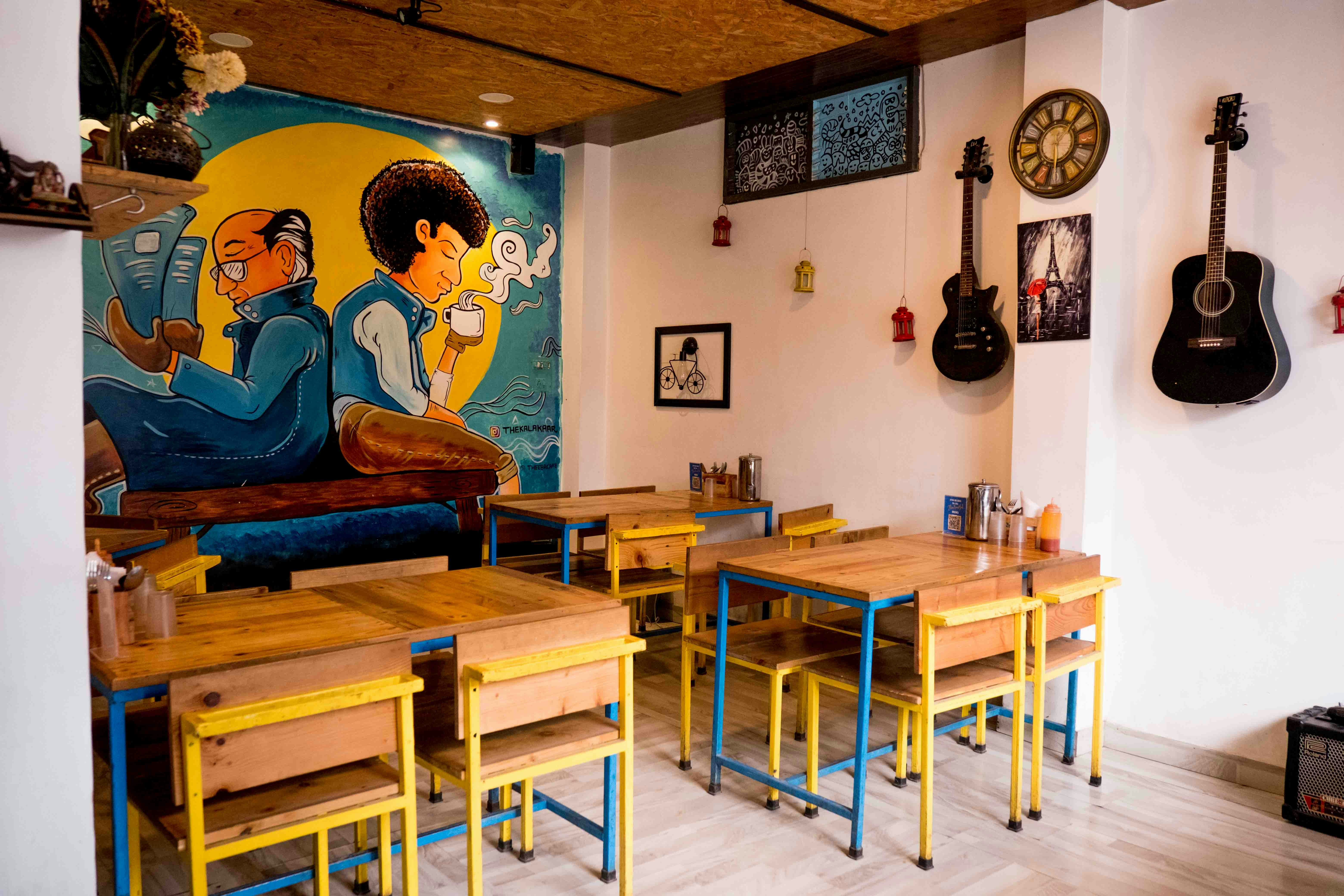 a room with many tables and chairs and a mural on the wall