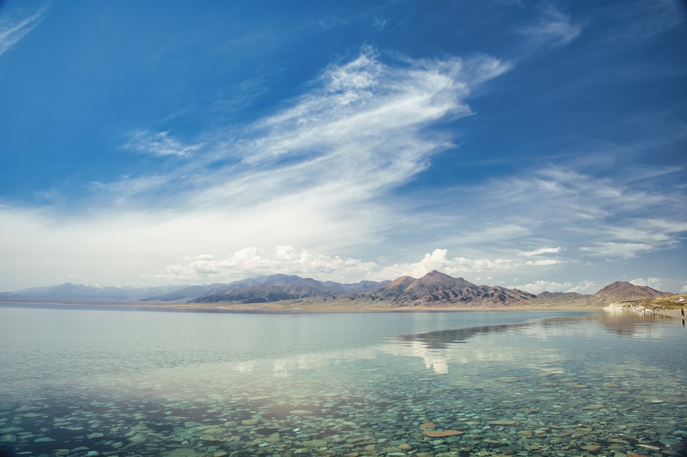 a body of water surrounded by mountains under a blue sky