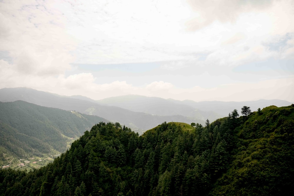 a scenic view of a mountain range with trees and mountains in the background