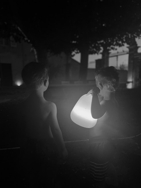 Children and parents walking along the eerie yet inviting haunted path lined with glowing lanterns