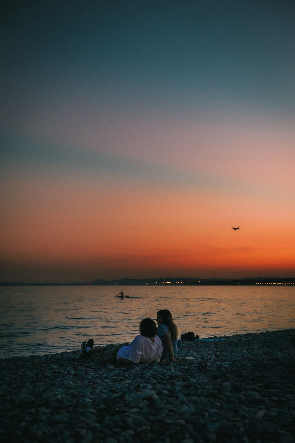 two people sitting on a beach at sunset