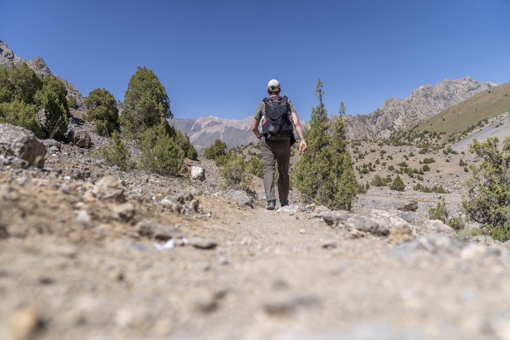 um homem caminhando por uma trilha nas montanhas