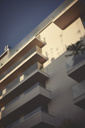 A sunlit modern apartment building with balconies overlooking a quiet street in Limassol.