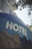 A large blue awning with the word 'HOTEL' prominently displayed in bold, white capital letters. Above the awning, parts of a building with balconies and some foliage from a tree are visible.