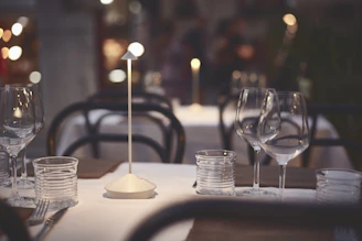 A serene dining table set with fine glassware, softly illuminated by warm light, with subtle sound wave graphics overlay.