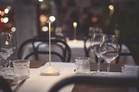 A serene dining table set with fine glassware, softly illuminated by warm light, with subtle sound wave graphics overlay.