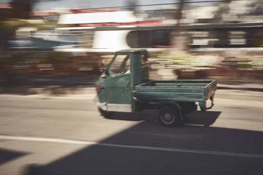 A small cargo truck navigating through city streets during the day.