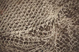 Close-up of intricate fishing nets spread out on a wooden dock.