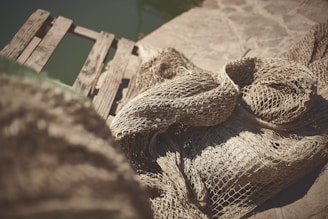 Close-up of sturdy fishing nets in natural beige tones draped over a wooden dock.