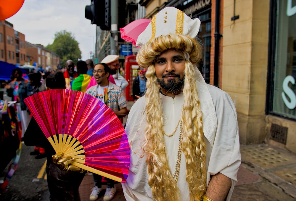 a man with long blonde hair holding a fan