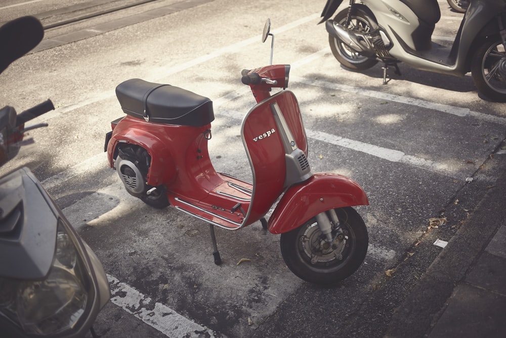 a red scooter is parked in a parking lot
