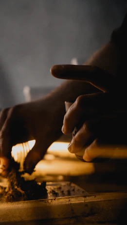 Close-up of artisan hands delicately shaping leather, illuminated by warm natural light.