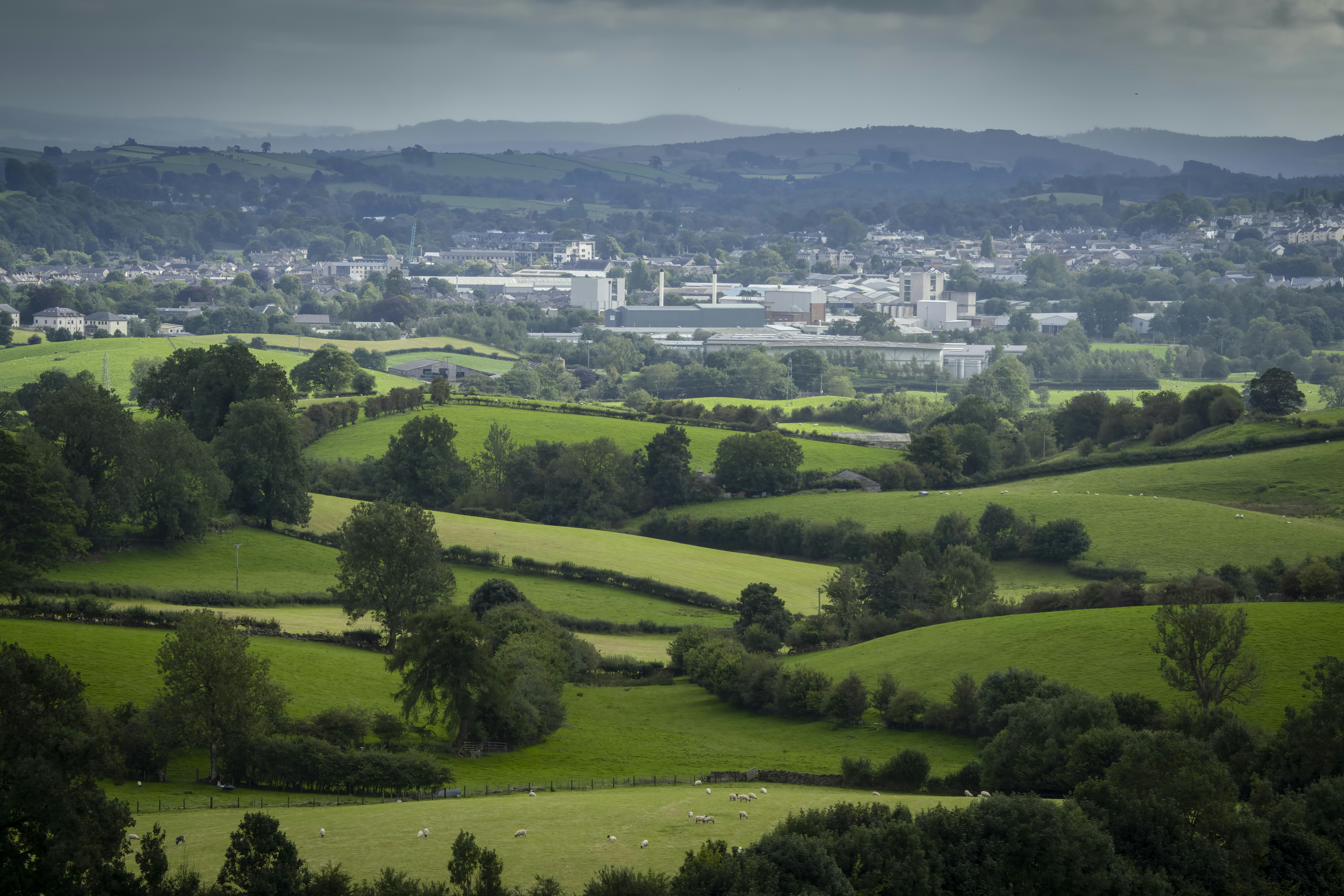 a view of a lush green countryside with a city in the distance