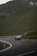A winding mountain road with a vintage car driving along.