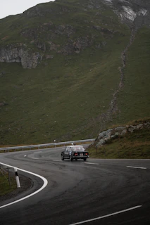 A vintage cab winding through misty mountain roads lined with rhododendrons.