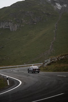 A winding mountain road with a vintage car driving along.