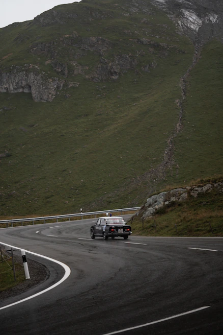 A vintage cab winding through misty mountain roads lined with rhododendrons.
