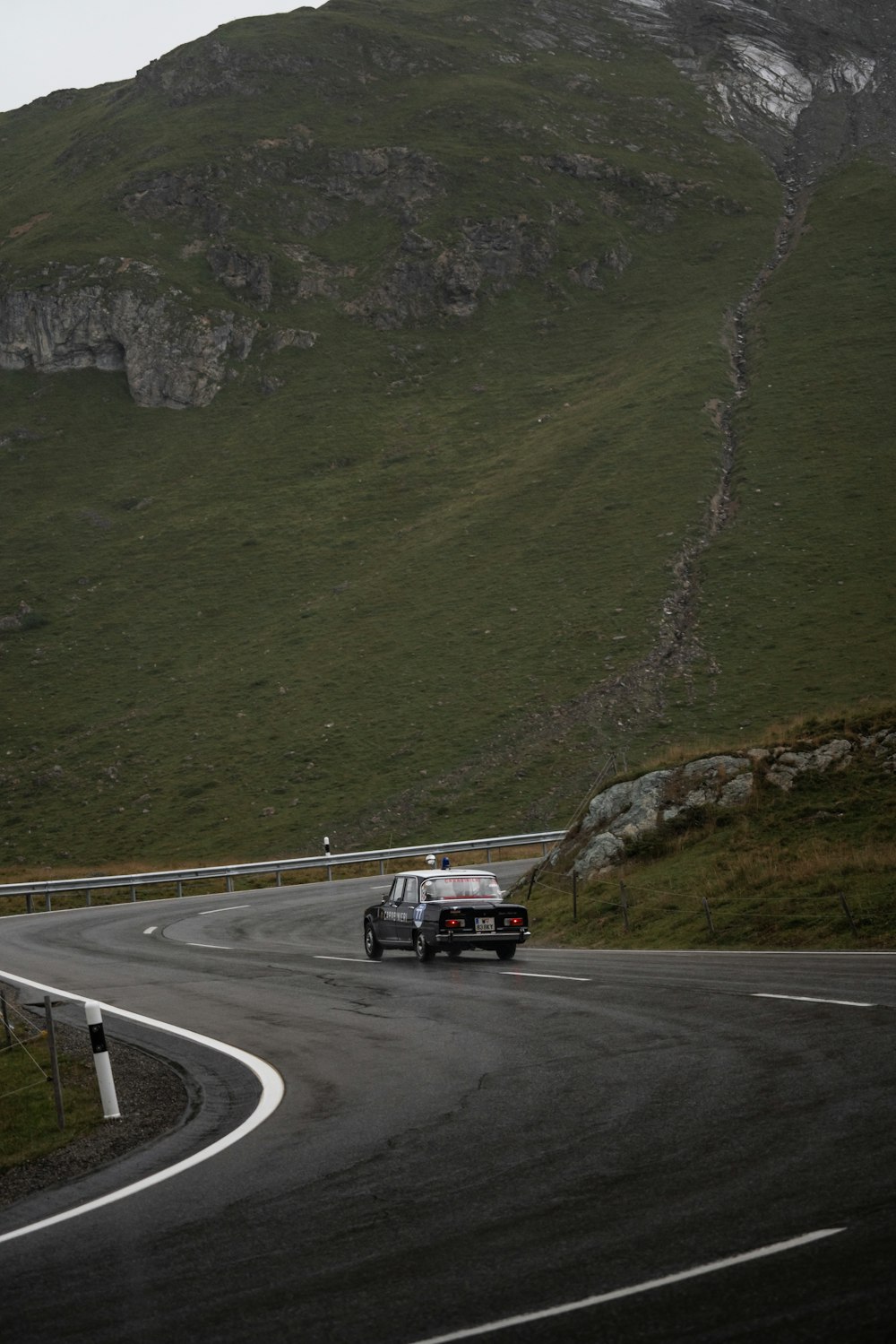 a car driving down a winding road with a mountain in the background